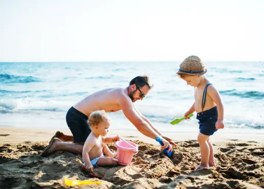 Photo of father playing with kids on the beach at a Caribbean resort.