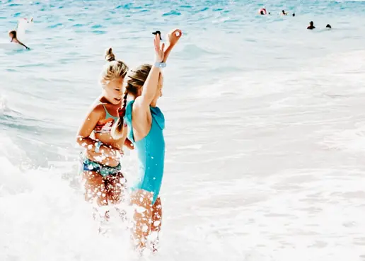 girls having fun in the waves at the beach.