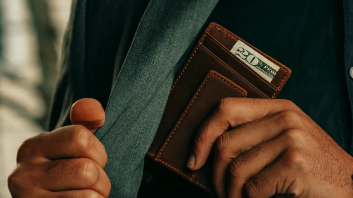 Man pulling out wallet to tip front desk at hotel.