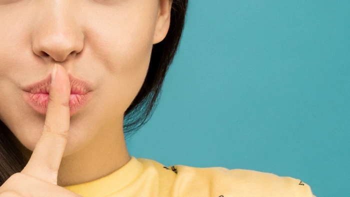 woman making a hush gesture after sharing a secret